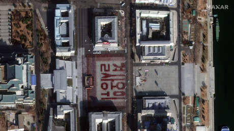 FOTO: Miles de norcoreanos crean con sus cuerpos la frase "defender con su vida" durante el ensayo de un desfile